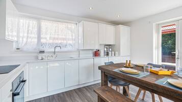Una cocina moderna con armarios blancos, una mesa de comedor de madera y un banco.