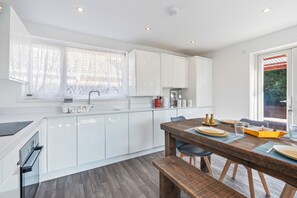Une cuisine moderne avec des meubles blancs, une table à manger en bois et un banc.