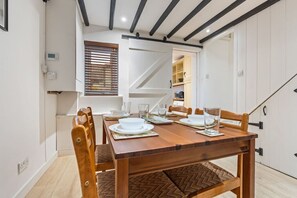 A dining area with a wooden table set for four, white plates, and a modern interior design. - Traditional 2 Bed Cottage, Otford, Games Room, Sleeps 4, Parking (Otford)
