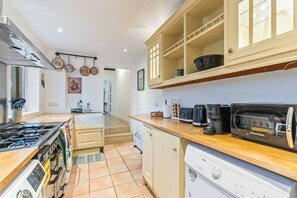 Eine Küche mit Gasherd, Backofen, Kaffeemaschine, Toaster und Geschirrspüler.