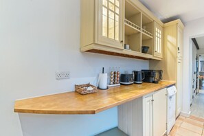 A kitchen with wooden cabinets, a countertop, and various appliances including a coffee maker and a kettle. - Traditional 2 Bed Cottage, Otford, Games Room, Sleeps 4, Parking (Otford)