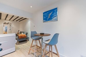 Ein modernes Wohnzimmer mit einer Couch, einem Esstisch mit Stühlen und einem Gemälde eines Flugzeugs an der Wand.