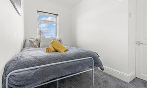 A bedroom with a single bed, a window with blinds, a door, and a carpeted floor. - Group Stays, Spacious 3 Bedroom House, Parking, Sleeps 6 (Swindon)