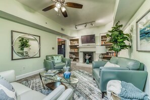 A living room with a ceiling fan, a fireplace, and a television. - Modern Historic District duplex spacious and short walk to parks and restaurants (Savannah)