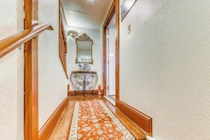A hallway with a wooden handrail, a patterned rug, a mirror, and a small table with a lamp. - Modern Historic District duplex spacious and short walk to parks and restaurants (Savannah)