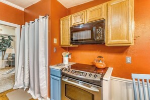 A kitchen with wooden cabinets, a microwave, an oven, and a kettle on the countertop. - Modern Historic District duplex spacious and short walk to parks and restaurants (Savannah)