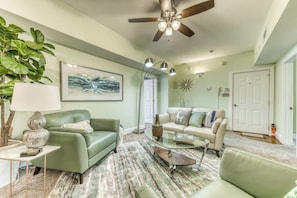 A living room with a ceiling fan, two sofas, a coffee table, and a large plant. - Modern Historic District duplex spacious and short walk to parks and restaurants (Savannah)