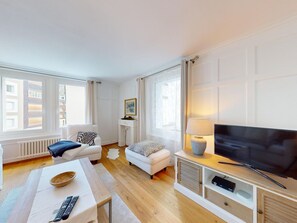 Una sala de estar moderna con una televisión de pantalla plana, un sofá, una mesita de centro y un pequeño taburete.