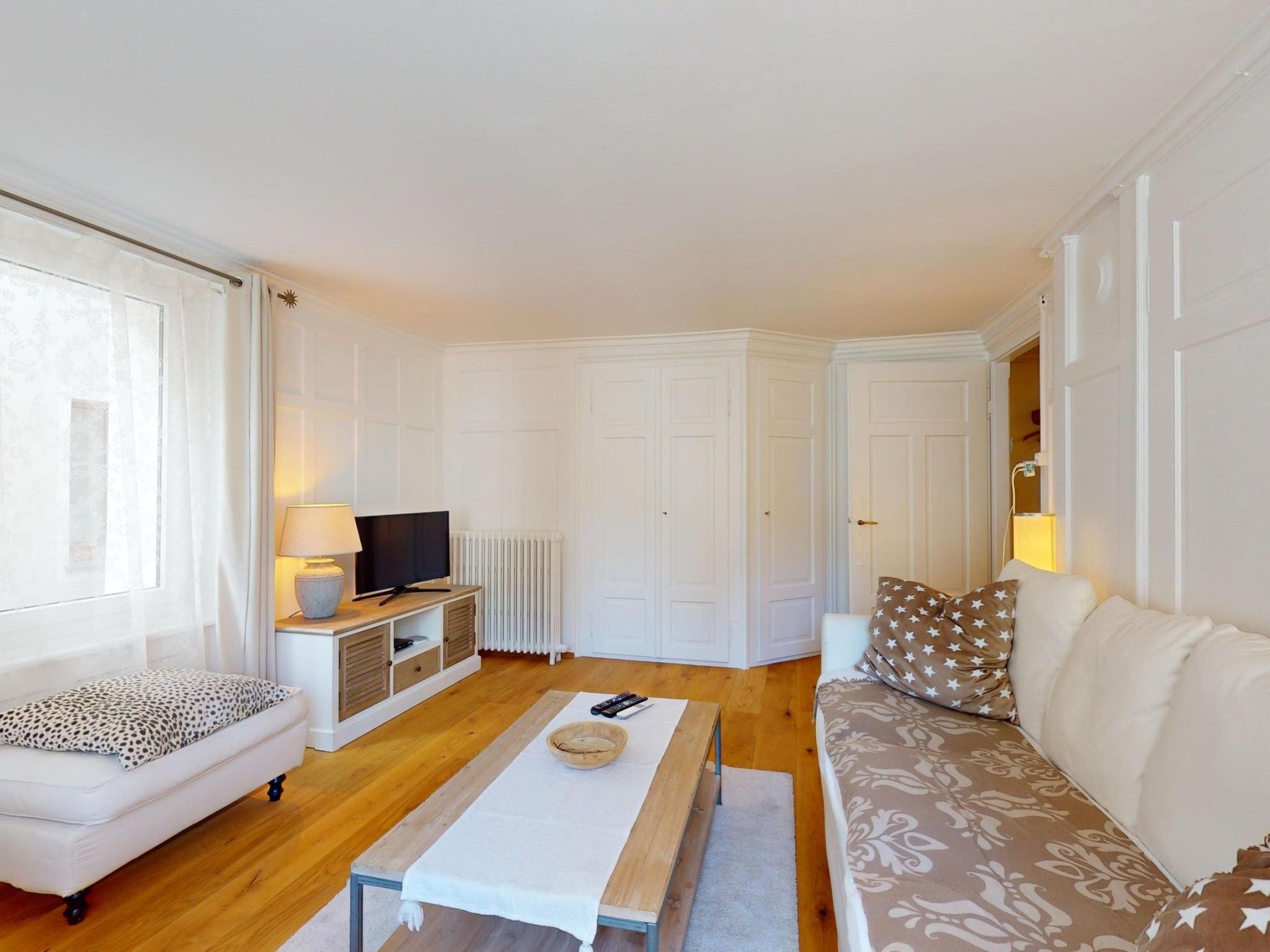 Ein Wohnzimmer mit einer Couch, einem Couchtisch, einem Fernseher und einem Schrank.