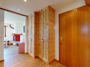A hallway with wooden doors and a wooden floor. There is a red bench and a white table in the background. - Apartment Cuntainta Madulain by Interhome (Madulain)