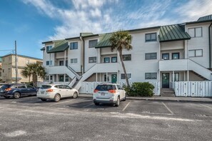 A multi-story building with a parking lot in front. - Oceanfront gem with spacious deck, direct beach access, & high-speed WiFi (Tybee Island)