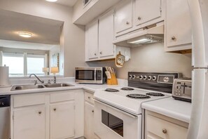 Une cuisine avec des meubles blancs, un four à micro-ondes, une cuisinière et un grille-pain.