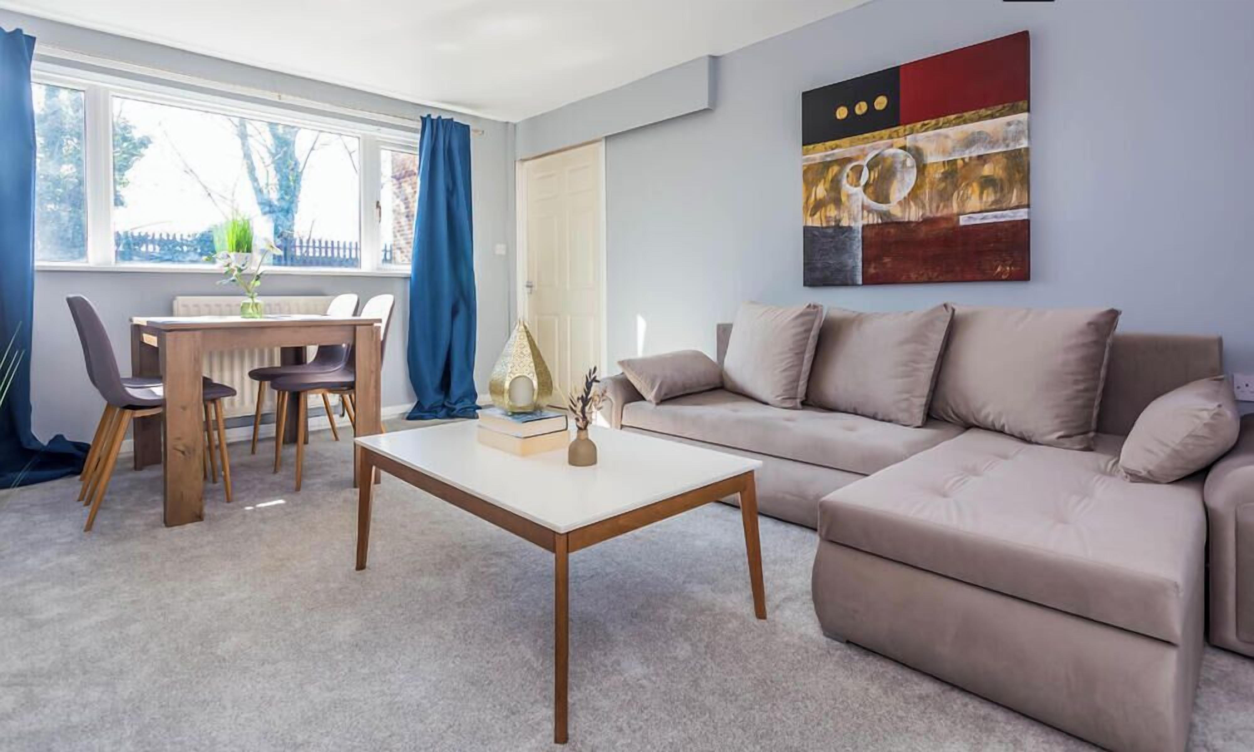 Ein Wohnzimmer mit Sofa, Couchtisch, Esstisch mit Stühlen und einem Bild an der Wand.