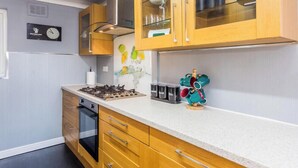 Una cucina con mobili in legno, un piano cottura a gas e una sveglia appesa al muro.