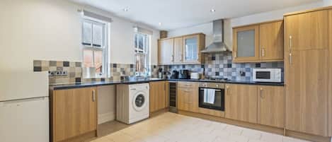 A modern kitchen with wooden cabinets, a built-in washing machine, and a microwave.