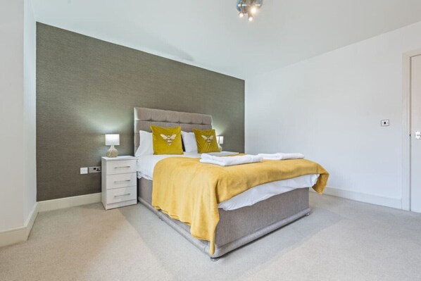 Ein Schlafzimmer mit einem Bett, Nachttischen und einer Wandeinrichtung.
