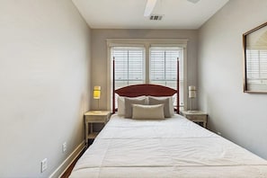 A bedroom with a bed, two bedside tables, a window with blinds, and a ceiling fan. - Newly Built Two-Story Townhouse w/Free WiFi, Washer/Dryer, and Central A/C (Savannah)