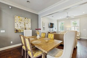 A dining area with a wooden table, chairs, and a painting on the wall. - Newly Built Two-Story Townhouse w/Free WiFi, Washer/Dryer, and Central A/C (Savannah)