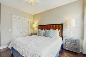 A bedroom with a large bed, two bedside lamps, a ceiling fan, and a white door. - Newly Built Two-Story Townhouse w/Free WiFi, Washer/Dryer, and Central A/C (Savannah)