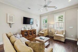 A living room with a sofa, armchairs, a coffee table, a TV, and a ceiling fan. - Newly Built Two-Story Townhouse w/Free WiFi, Washer/Dryer, and Central A/C (Savannah)