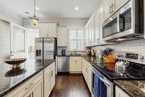A kitchen with white cabinets, a stainless steel refrigerator, a microwave, and a stove. - Newly Built Two-Story Townhouse w/Free WiFi, Washer/Dryer, and Central A/C (Savannah)
