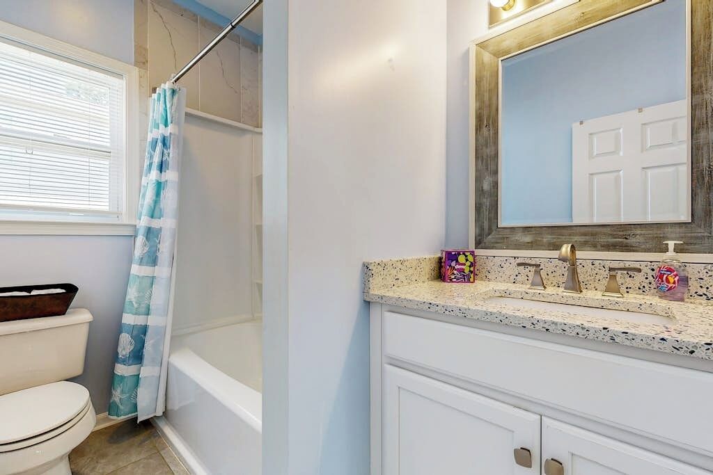 A bathroom with a shower, toilet, and sink with a mirror above.