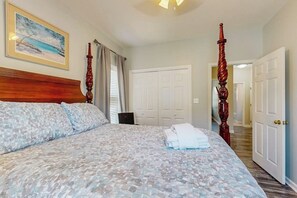 Ein Schlafzimmer mit einem Bett, einem Bild an der Wand und einer Tür zu einem anderen Raum.