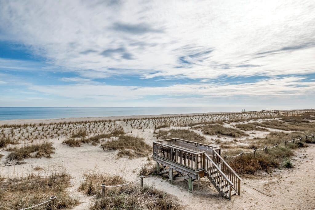 A beach with a wooden boardwalk leading to a viewing platform.