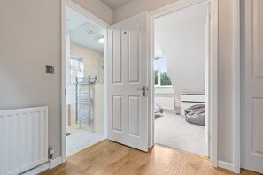 A room with a wooden floor, a radiator, a towel rack, and a door leading to another room. - Large 4 Bedroom House Bricket Wood, Van & Car Parking, Sleeps 8 (Bricket Wood)