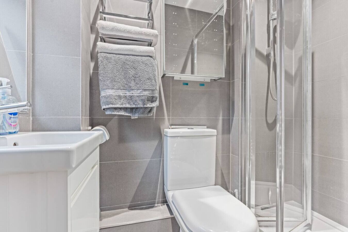 A modern bathroom with a toilet, a shower enclosure, and a towel rack.