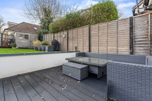 Eine Terrasse mit Glastisch und gepolsterten Sitzgelegenheiten.