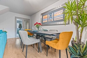 A dining area with a table set for four, surrounded by chairs, a window with a view, and a potted plant. - Large 4 Bedroom House Bricket Wood, Van & Car Parking, Sleeps 8 (Bricket Wood)
