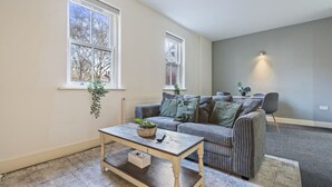 Ein Wohnzimmer mit einer Couch, einem Couchtisch und einer Topfpflanze.