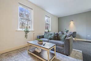 A living room with a sofa, a coffee table, and a potted plant. - Central Derby Stay | Comfort for 4 | Wi-Fi (Derby)
