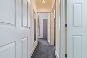 A hallway with white doors, a carpeted floor, and a ceiling light. - Central Derby Stay | Comfort for 4 | Wi-Fi (Derby)