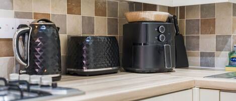 A kitchen with a kettle, toaster, and coffee maker on the countertop.