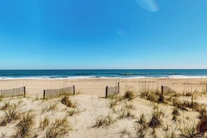 Una spiaggia con una recinzione di legno e dune.