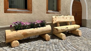 Un espace extérieur aménagé dans un style rustique, avec des bancs en bois et un jardinier.
