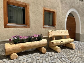 Ein rustikaler Sitzbereich im Freien mit Holzbanken und einem Blumenbeet.