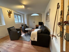 Ein modernes Wohnzimmer mit Sofa, Sesseln, Couchtisch und Fernseher.