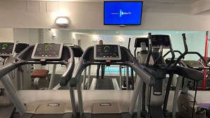 Une salle de sport équipée de tapis de course, d’un écran de télévision et d’un miroir.