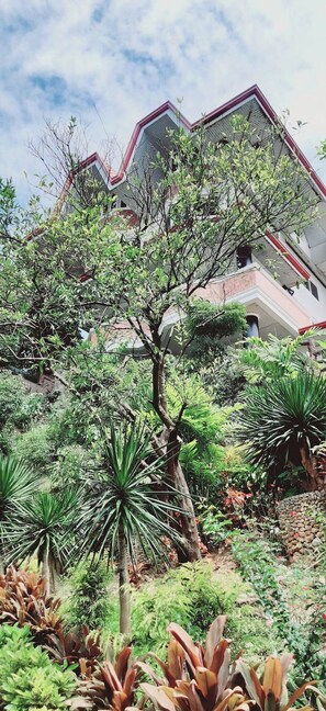 A building with a unique angular design, surrounded by lush greenery and various plants. - Avana Hills Boracay Prime - Family (Boracay Island)