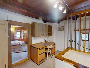 A room with a wooden desk, a chair, a bed, and a staircase. - Apartment Seraina by Interhome (La Punt-Chamues-ch)