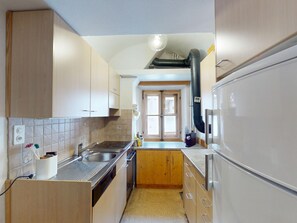 A compact kitchen with a built-in dishwasher, a stove, and a refrigerator. - Apartment Seraina by Interhome (La Punt-Chamues-ch)