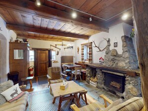 A rustic interior with a stone fireplace, wooden furniture, and a dining area. - Apartment Seraina by Interhome (La Punt-Chamues-ch)