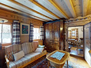 A cozy cabin interior with a wooden sofa, a small wooden table, and a large cabinet. - Apartment Seraina by Interhome (La Punt-Chamues-ch)