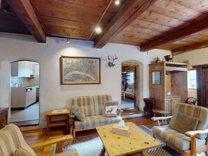 A cozy living room with a wooden ceiling, a sofa, a coffee table, and a framed map on the wall. - Apartment Seraina by Interhome (La Punt-Chamues-ch)