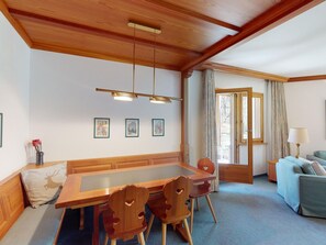 Ein Essbereich mit Holztisch und -stühlen, einer Kristallleuchtre und gerahmten Bildern an der Wand.