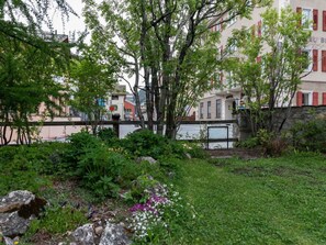Ett hotell med en trädgård, en stenmur och utsikt över gatan.