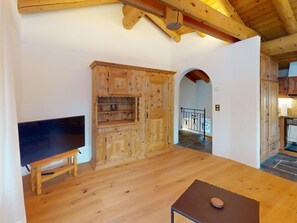 A room with a wooden TV stand, a cabinet with multiple compartments, and a stone-tiled floor. - Apartment Alvetern by Interhome (Sils Maria)